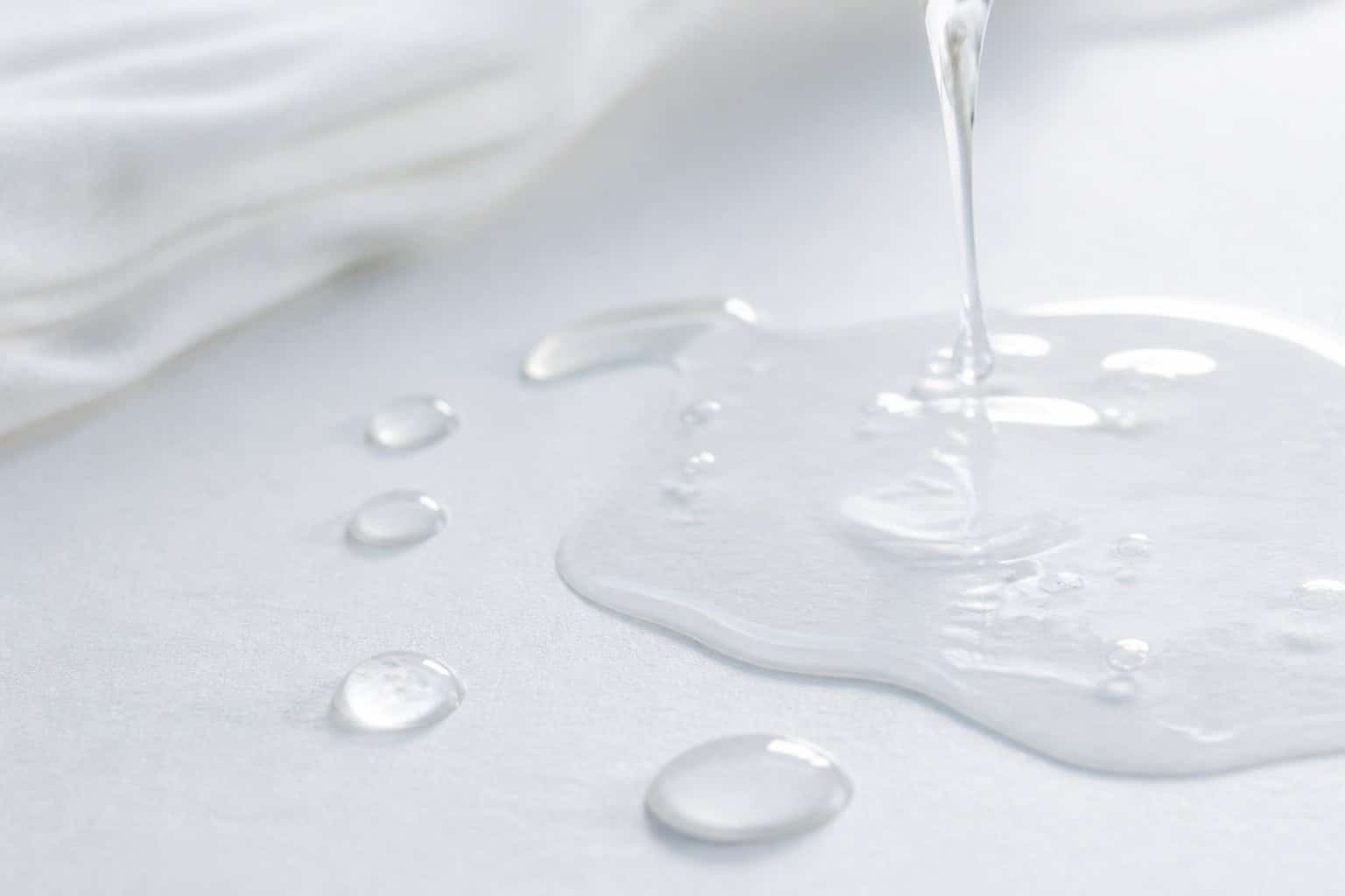 Gotas de líquido transparente sobre uma superfície branca limpa, representando menstruação líquida.